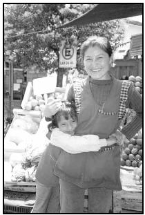 An Argentine fruit and vegetable vendor and her daughter greet customers at a market. Cory Langley