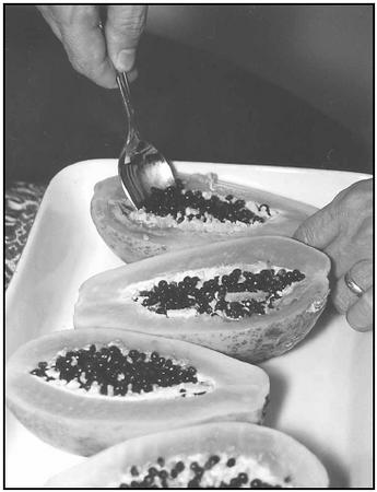 Arrange the peeled papaya halves, cut side up, in a baking dish. Scoop out the seeds before baking the papaya dessert. EPD Photos